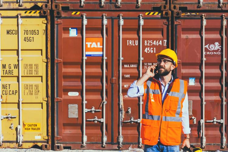 Supply chain professional next to shipping containers